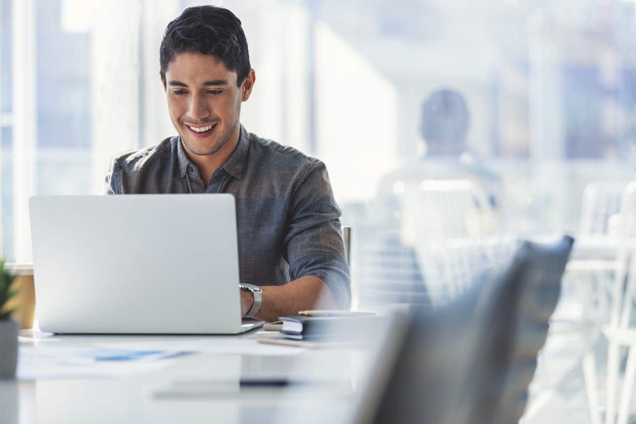 man smiling while working on laptop